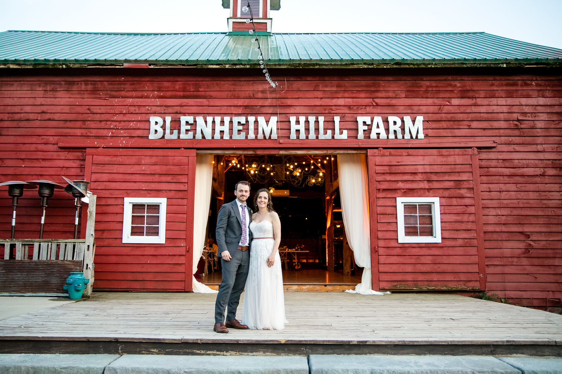 A bride and groom in front of a beautifully decorated barn at Blenheim Hill Farm