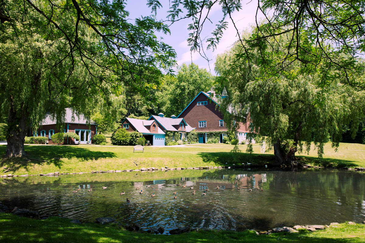 Idyllic scene of Stonover Farm surrounded by lush green trees and a tranquil pond reflecting the buildings in the peaceful Berkshire setting