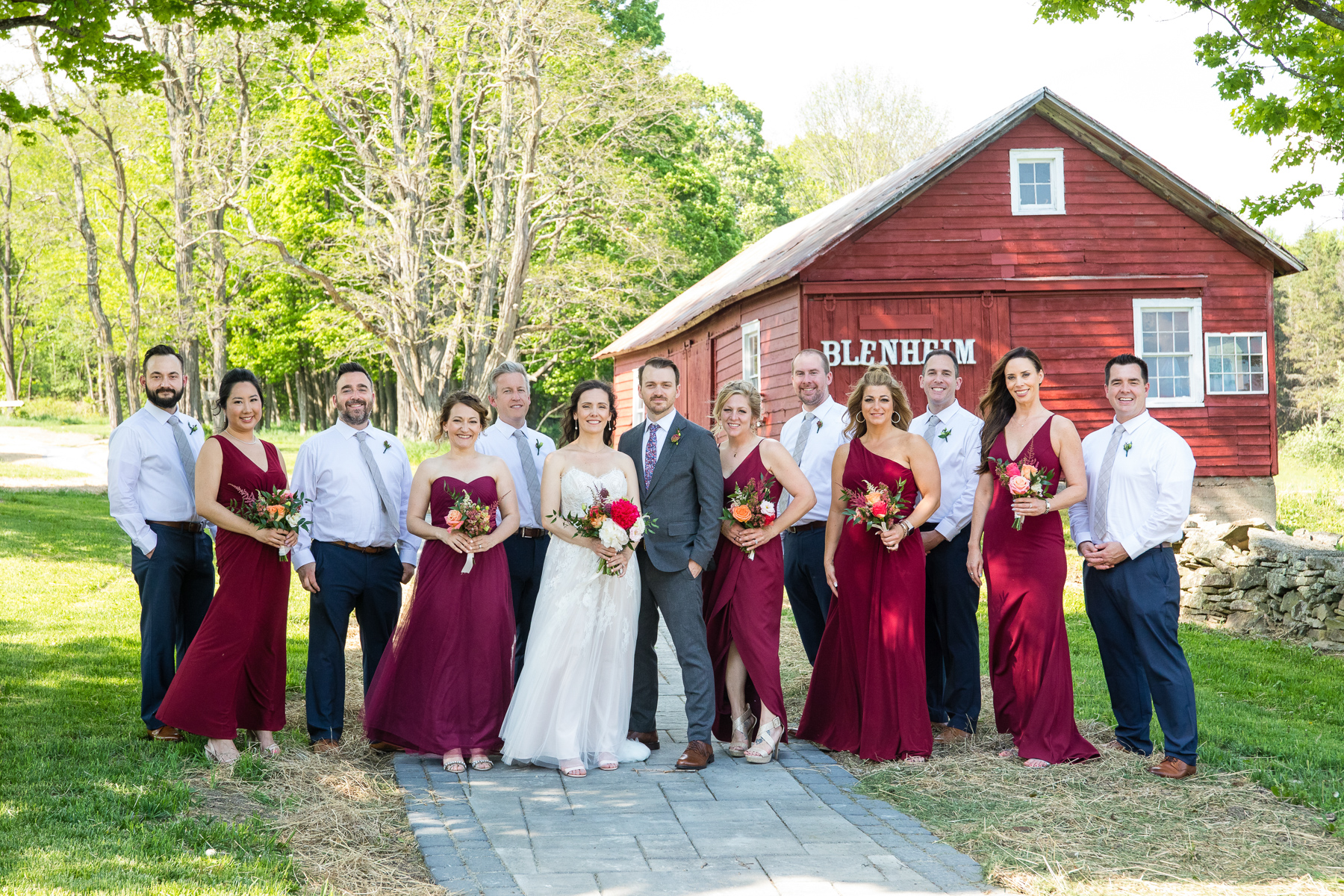 The wedding party posing for a group photo in front of the barn at Blenheim Hill Farm