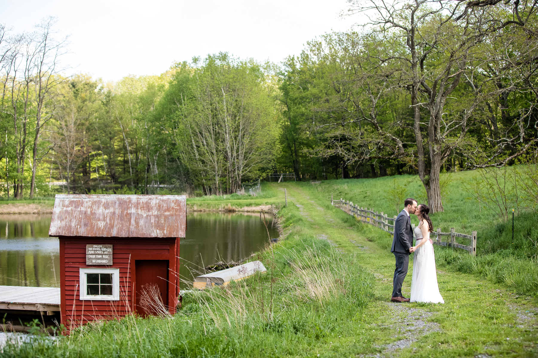 The bride and groom sharing a kiss in front of the pond at Blenheim Hill Farm