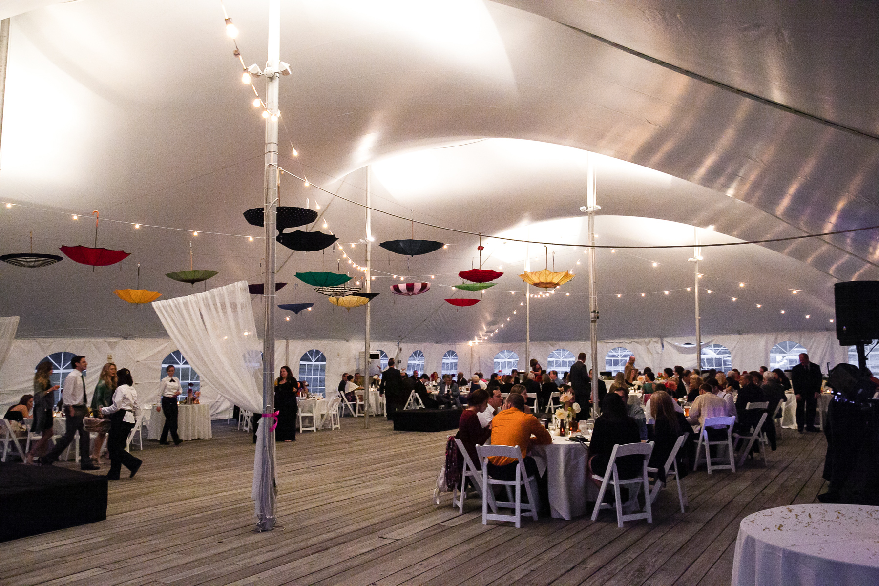 The reception tent decorated with vintage umbrellas and cafe lights, creating a romantic ambiance