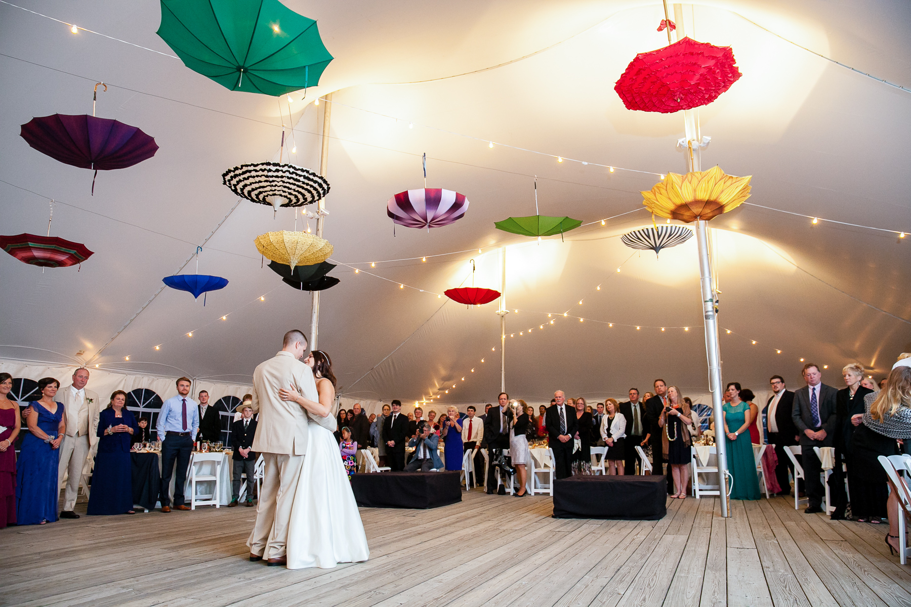 The bride and groom enjoying their first dance together in the tent, surrounded by loved ones