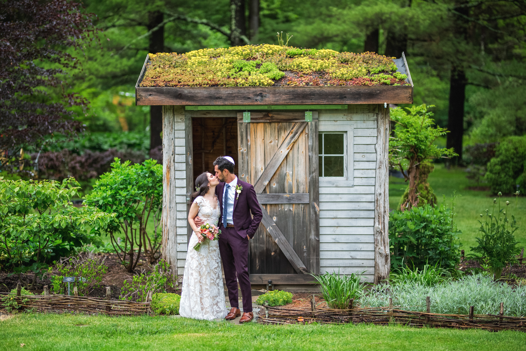bride and groom kissing in front of a garden shed at the Berkshire Botanical Gardens