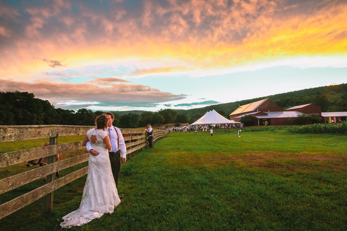 bride and groom kissing with a sunset at hancock shaker village